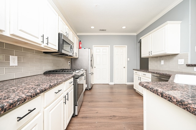 kitchen with dark stone counters, dark hardwood / wood-style floors, tasteful backsplash, white cabinetry, and appliances with stainless steel finishes