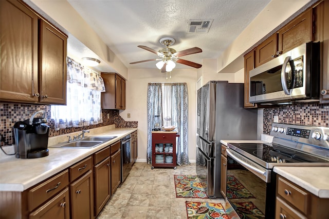 kitchen with ceiling fan, a textured ceiling, stainless steel appliances, and tasteful backsplash