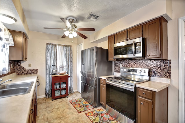 kitchen with ceiling fan, sink, tasteful backsplash, a textured ceiling, and appliances with stainless steel finishes