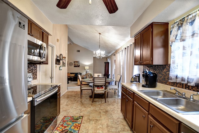 kitchen with pendant lighting, a textured ceiling, ceiling fan with notable chandelier, vaulted ceiling, and stainless steel appliances