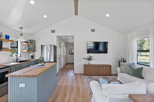 living room featuring high vaulted ceiling, light hardwood / wood-style floors, a healthy amount of sunlight, and sink