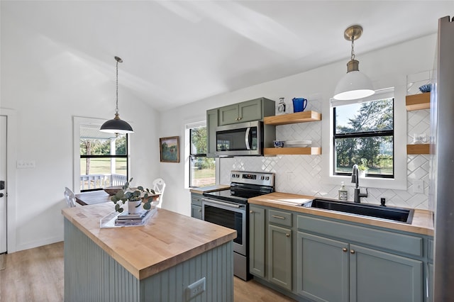 kitchen featuring light wood-type flooring, sink, hanging light fixtures, appliances with stainless steel finishes, and butcher block countertops