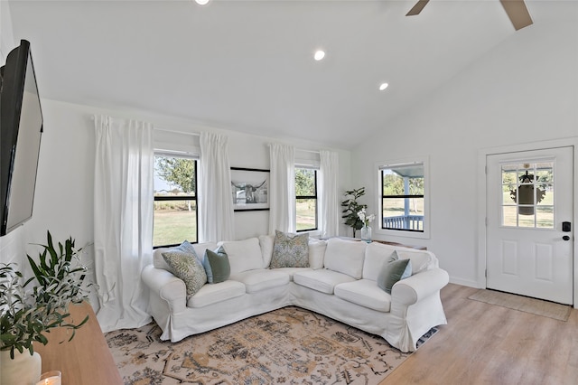 living room with high vaulted ceiling, light wood-type flooring, ceiling fan, and plenty of natural light