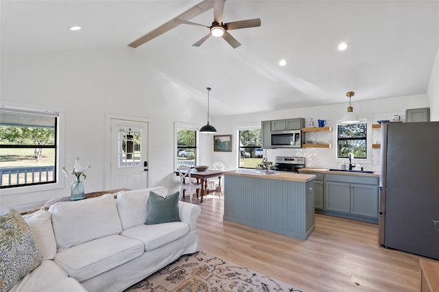 living room with ceiling fan, sink, light hardwood / wood-style floors, and high vaulted ceiling