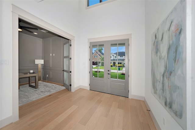 entrance foyer featuring ceiling fan, a towering ceiling, light hardwood / wood-style floors, and french doors