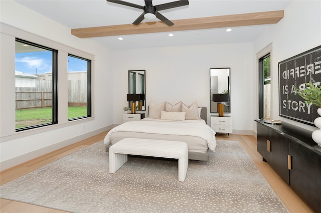 bedroom with light wood-type flooring, multiple windows, beamed ceiling, and ceiling fan