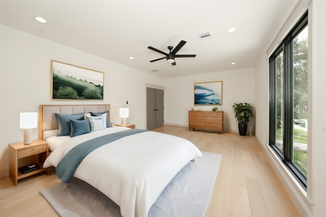 bedroom with ceiling fan, light hardwood / wood-style floors, and multiple windows