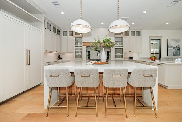 kitchen with white cabinetry, a large island, pendant lighting, and light hardwood / wood-style flooring