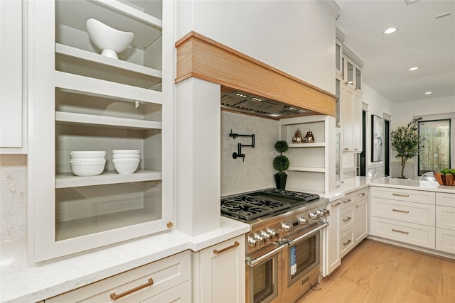 kitchen featuring light hardwood / wood-style flooring, range with two ovens, backsplash, and light stone countertops