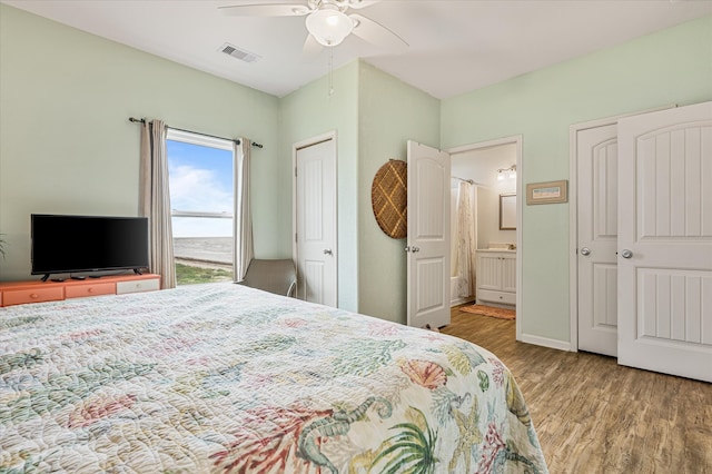 bedroom with ceiling fan, ensuite bath, and hardwood / wood-style floors