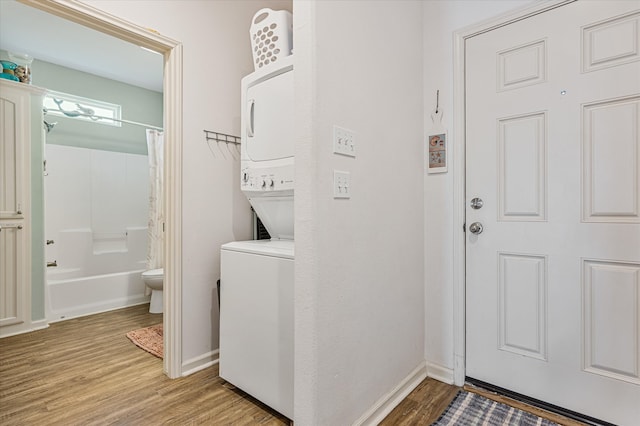 clothes washing area with stacked washer and clothes dryer and light wood-type flooring