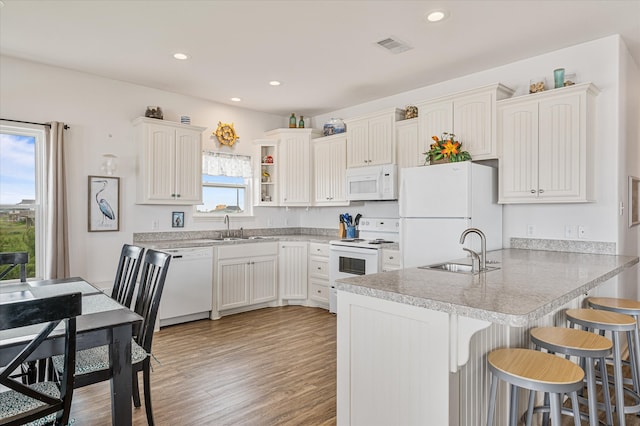 kitchen with white cabinets, light wood-type flooring, sink, and white appliances