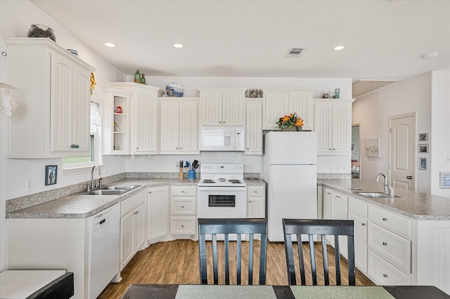 kitchen with white cabinetry, white appliances, a kitchen island, wood-type flooring, and sink