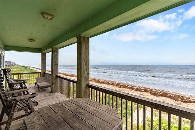 wooden deck featuring a beach view and a water view