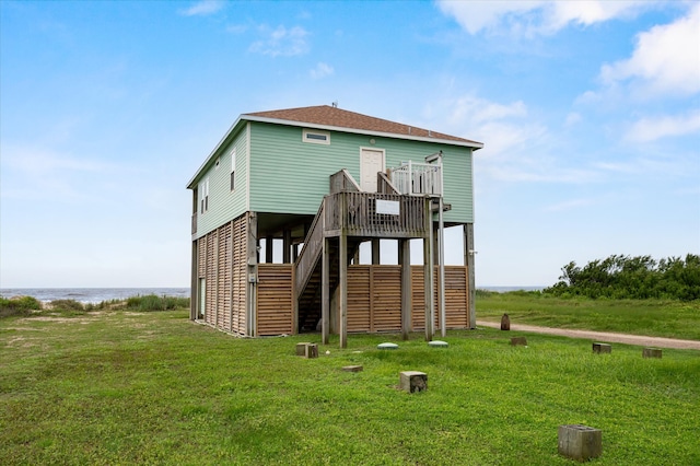 rear view of house featuring a lawn and a deck with water view