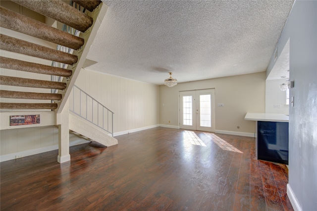 unfurnished living room with a textured ceiling, french doors, and dark hardwood / wood-style floors