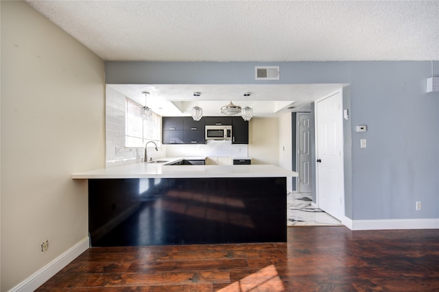 kitchen featuring a textured ceiling, kitchen peninsula, sink, and dark hardwood / wood-style floors