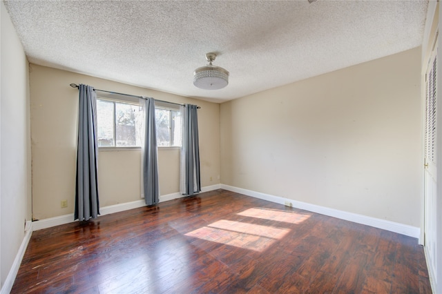 spare room with a textured ceiling and dark hardwood / wood-style floors