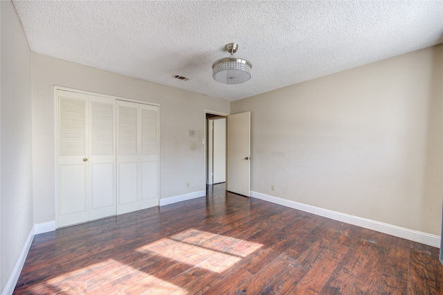 unfurnished bedroom with a textured ceiling, a closet, and dark hardwood / wood-style floors