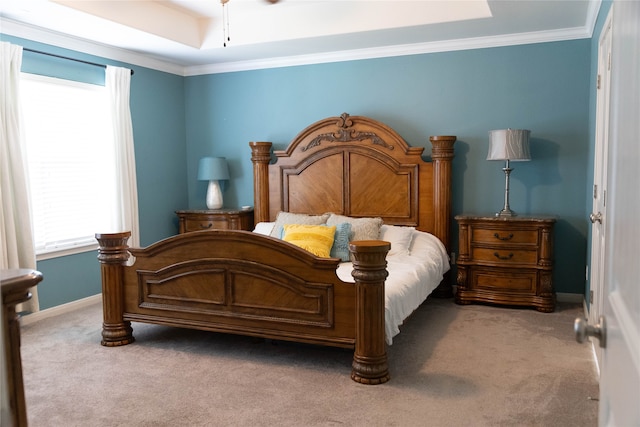 bedroom with a tray ceiling, crown molding, and carpet flooring