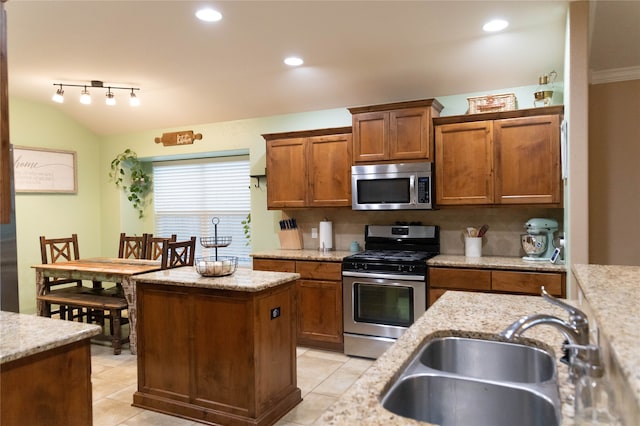 kitchen with a center island, sink, decorative backsplash, appliances with stainless steel finishes, and light stone countertops