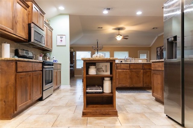 kitchen featuring tasteful backsplash, vaulted ceiling, appliances with stainless steel finishes, ornamental molding, and ceiling fan