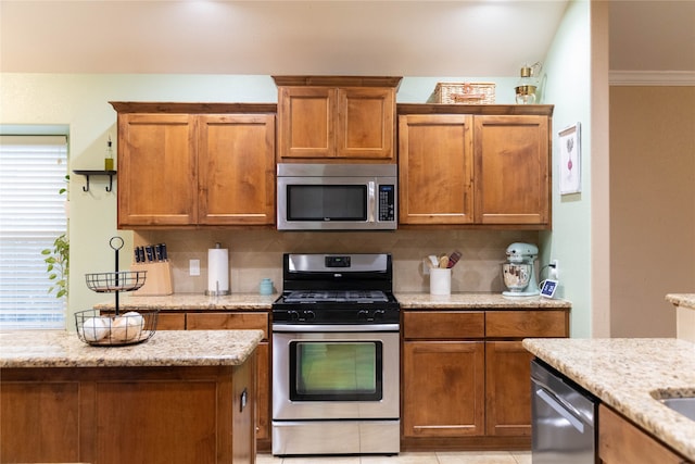 kitchen featuring ornamental molding, backsplash, appliances with stainless steel finishes, and light stone counters