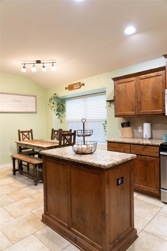 kitchen featuring stainless steel range oven, a center island, light tile patterned floors, and light stone counters