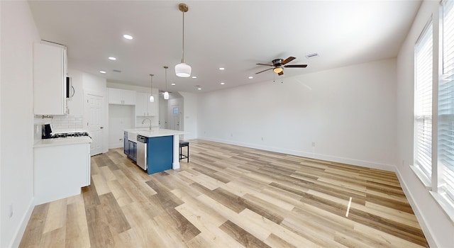 kitchen with a kitchen island with sink, white cabinets, blue cabinetry, pendant lighting, and light hardwood / wood-style flooring