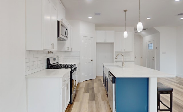 kitchen with light hardwood / wood-style flooring, sink, hanging light fixtures, white cabinets, and appliances with stainless steel finishes