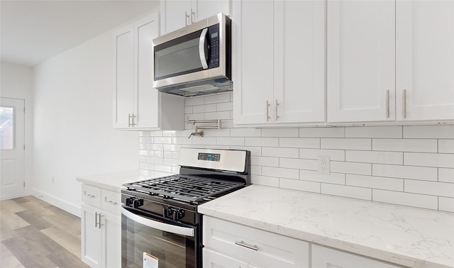 kitchen with white cabinets, stainless steel appliances, and light hardwood / wood-style floors