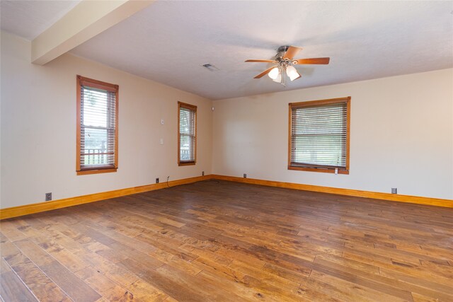 empty room featuring ceiling fan, beamed ceiling, and wood-type flooring