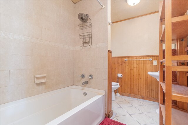 bathroom featuring wooden walls, tiled shower / bath combo, tile patterned floors, and toilet