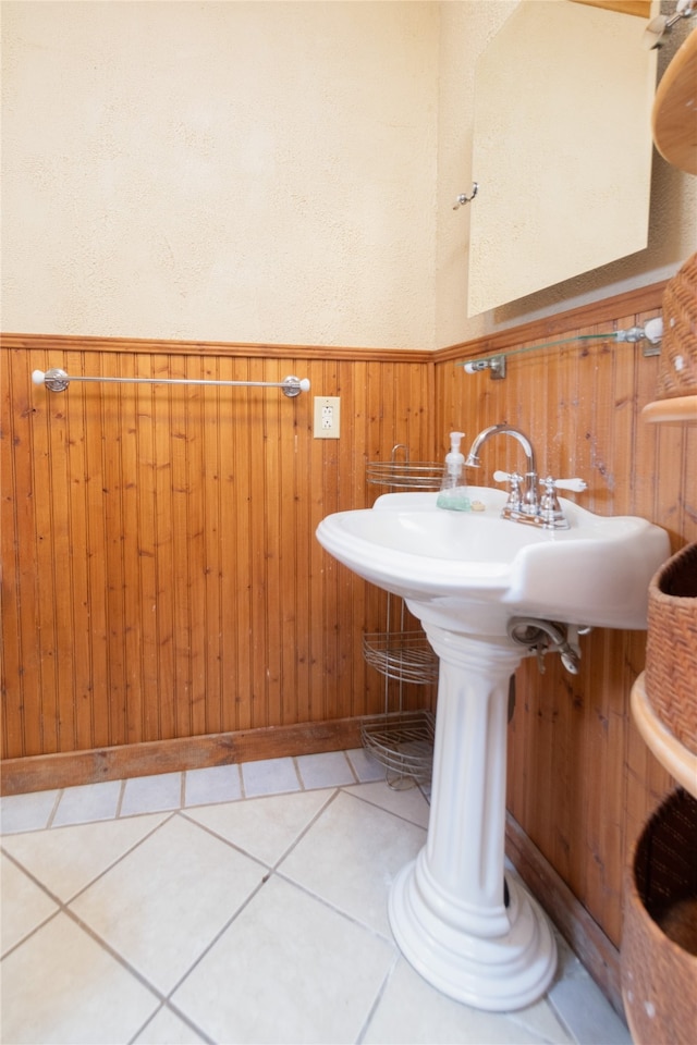 bathroom with tile patterned flooring and wood walls