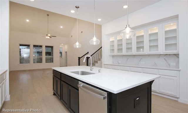 kitchen featuring tasteful backsplash, an island with sink, white cabinetry, stainless steel dishwasher, and sink