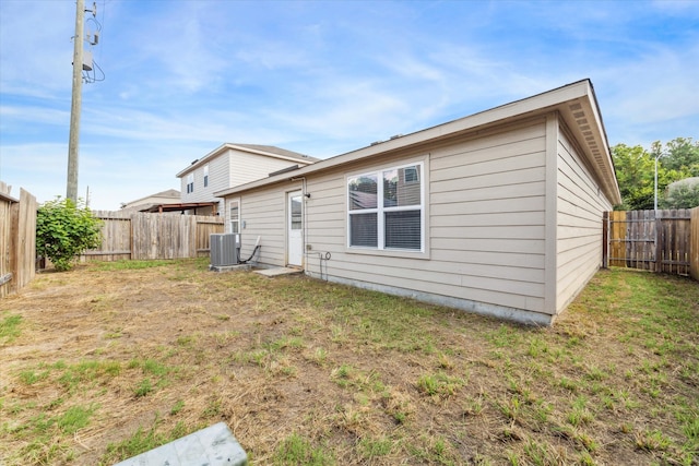 back of property featuring a lawn and central AC