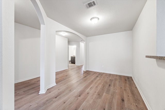 unfurnished room with a textured ceiling and light hardwood / wood-style flooring