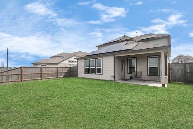 rear view of house featuring a lawn, a patio, and solar panels