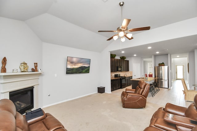 living room featuring ceiling fan, light colored carpet, sink, and vaulted ceiling