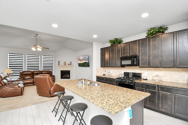 kitchen with a kitchen island with sink, sink, and black appliances