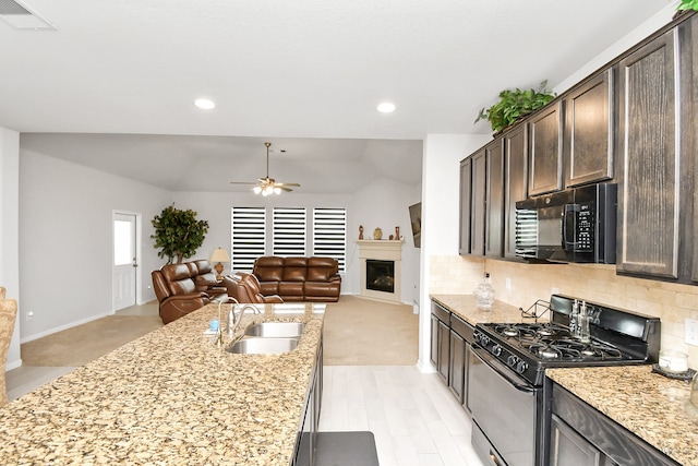 kitchen with black appliances, dark brown cabinetry, sink, and light stone countertops