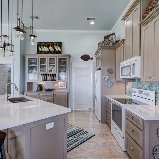 1038 Elizabeth St, Gilchrist, TX 77617 - kitchen with white appliances, a sink, decorative backsplash, light countertops, and crown molding