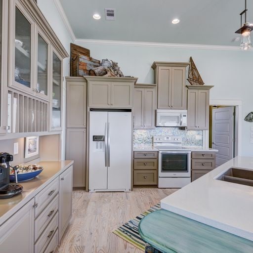 kitchen featuring decorative backsplash, crown molding, light hardwood / wood-style flooring, and white appliances