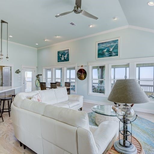 living room featuring ceiling fan, lofted ceiling, a wealth of natural light, and light hardwood / wood-style flooring