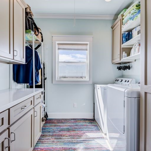 clothes washing area with separate washer and dryer, crown molding, and cabinets