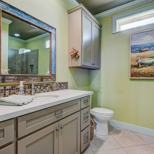 bathroom with tasteful backsplash, tile patterned flooring, toilet, vanity, and ornamental molding