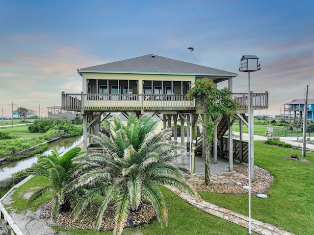 1038 Elizabeth St, Gilchrist, TX 77617 - rear view of property with a sunroom, a shingled roof, a yard, a patio, and a deck with water view