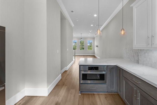 kitchen with kitchen peninsula, decorative backsplash, light hardwood / wood-style flooring, ornamental molding, and stainless steel oven