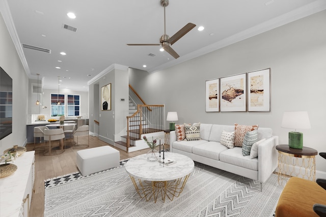 living room with ceiling fan, light wood-type flooring, and crown molding