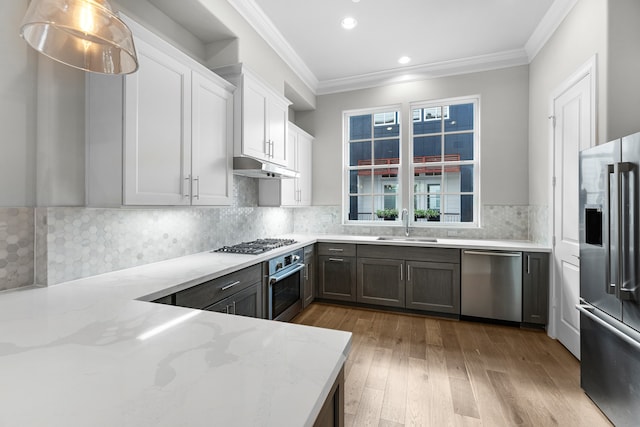 kitchen with white cabinets, light wood-type flooring, hanging light fixtures, appliances with stainless steel finishes, and light stone countertops